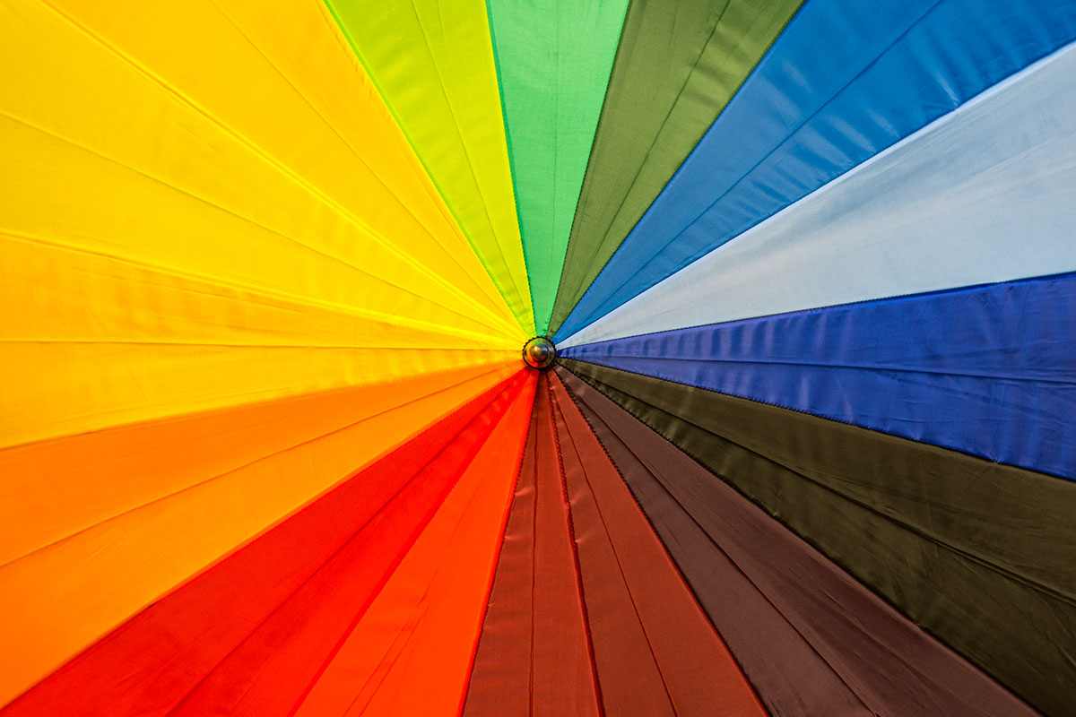 top-down view of umbrella with panels radiating a spectrum of colours including yellow, orange, red, maroon, brown, dark green, light blue & royal blue