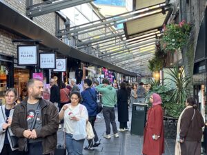 busy market street with people walking, shopping, & eating