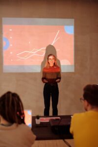 a woman presenting in front of an audience in a modern meeting