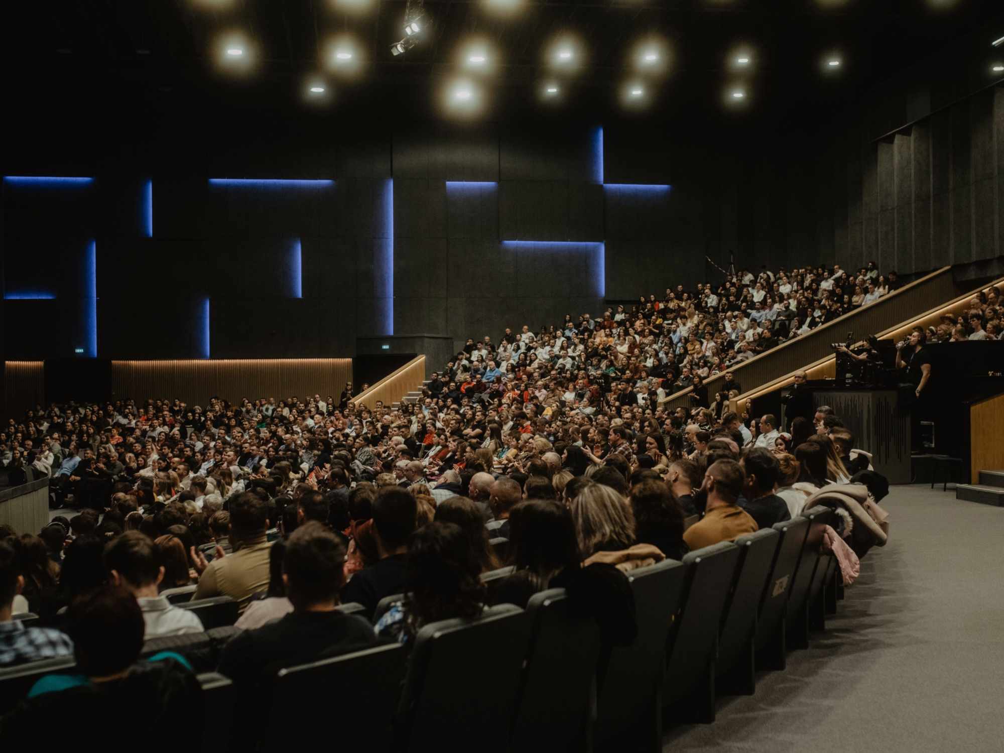 large, modern auditorium filled with a packed audience