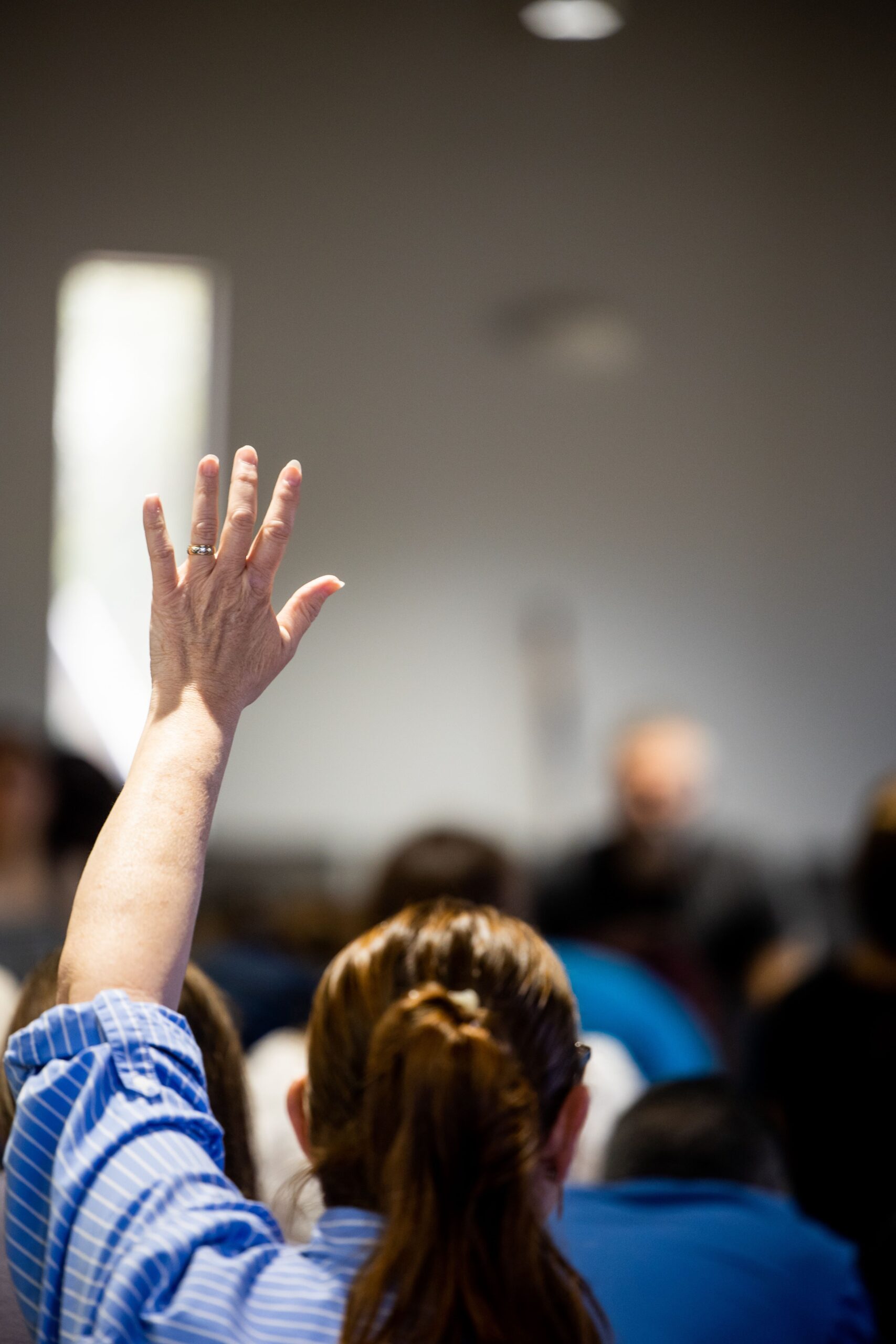 Question Hand-Up Image person raising their hand during a presentation